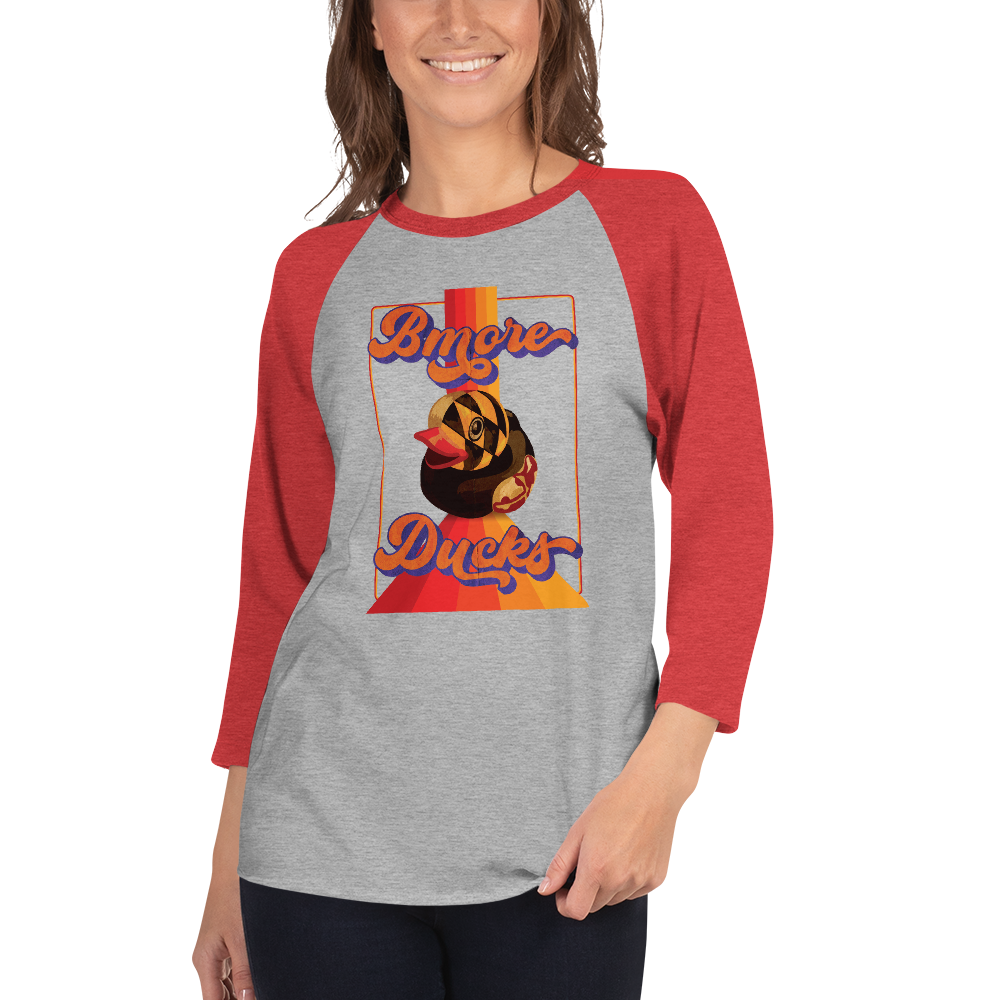 woman wearing a red sleeve, gray centered raglan shirt with a vintage 1970's design that says "Bmore Ducks" and features a Maryland flag rubber duck
