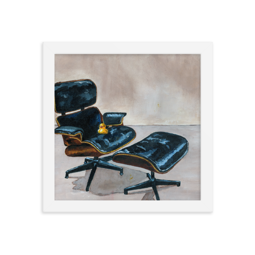 10x10 Framed print of a rubber duck sitting in a black Eames chair. Framed in white