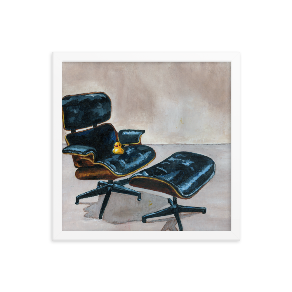 14x14 Framed print of a rubber duck sitting in a black Eames chair. Framed in white