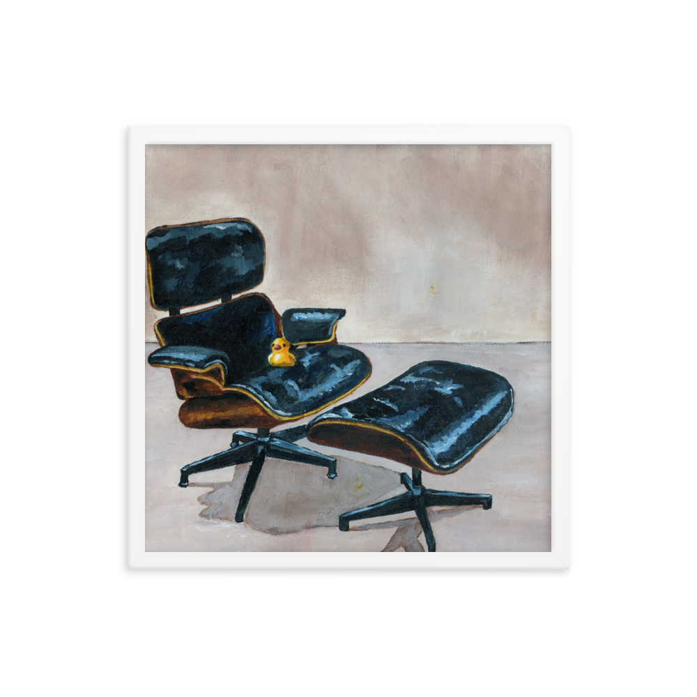 18x18 Framed print of a rubber duck sitting in a black Eames chair. Framed in white