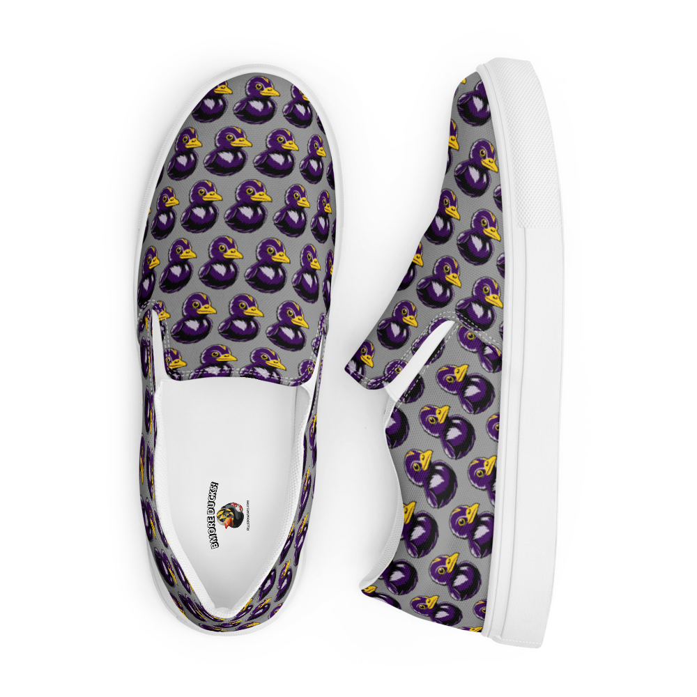 top view of mens slip-on canvas shoes with a black and purple rubber duck logo pattern over gray background